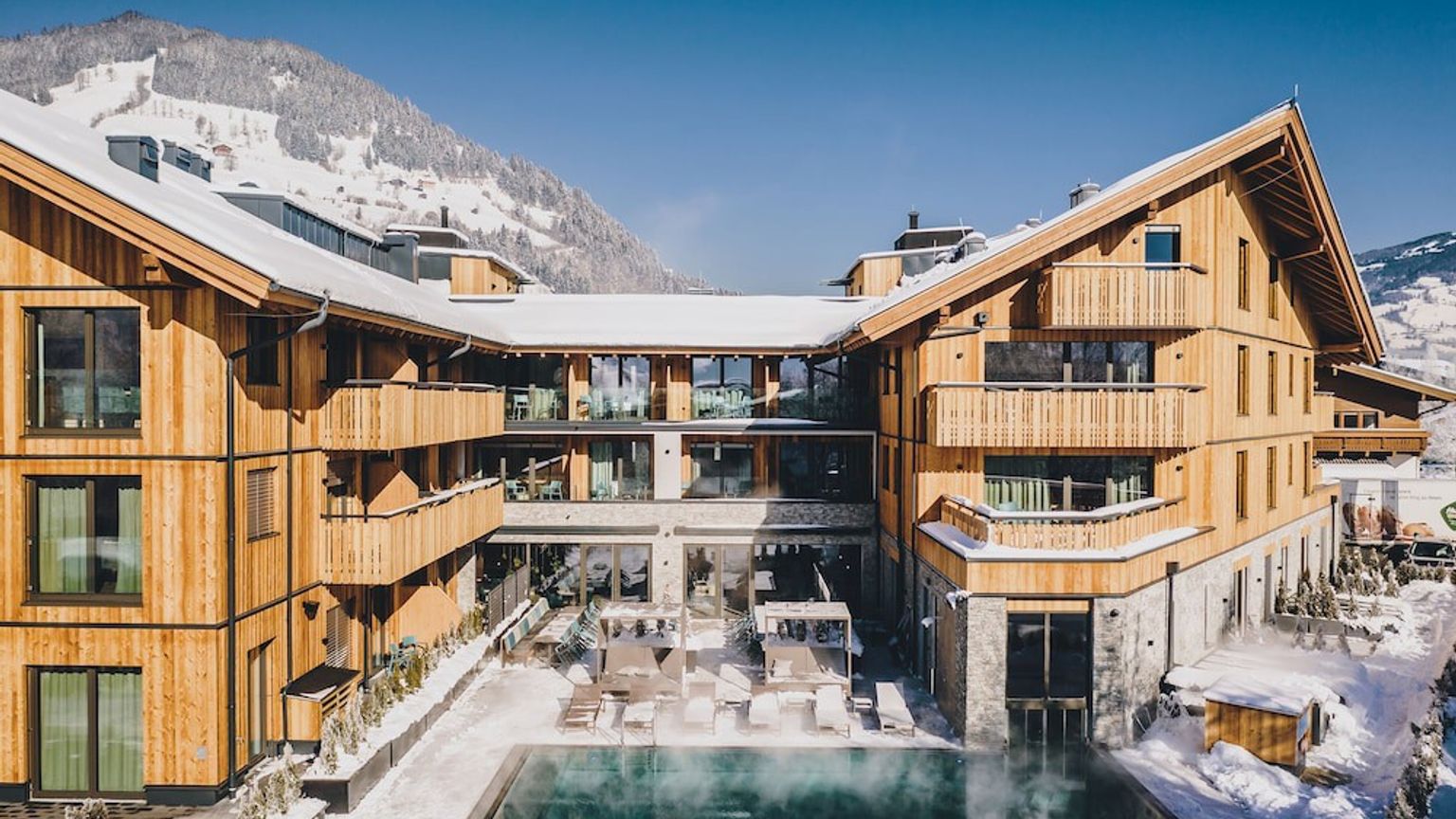 een groot houten gebouw met een zwembad in het midden ervan in de sneeuw, Elements Resort Zell am See, BW Signature Collection