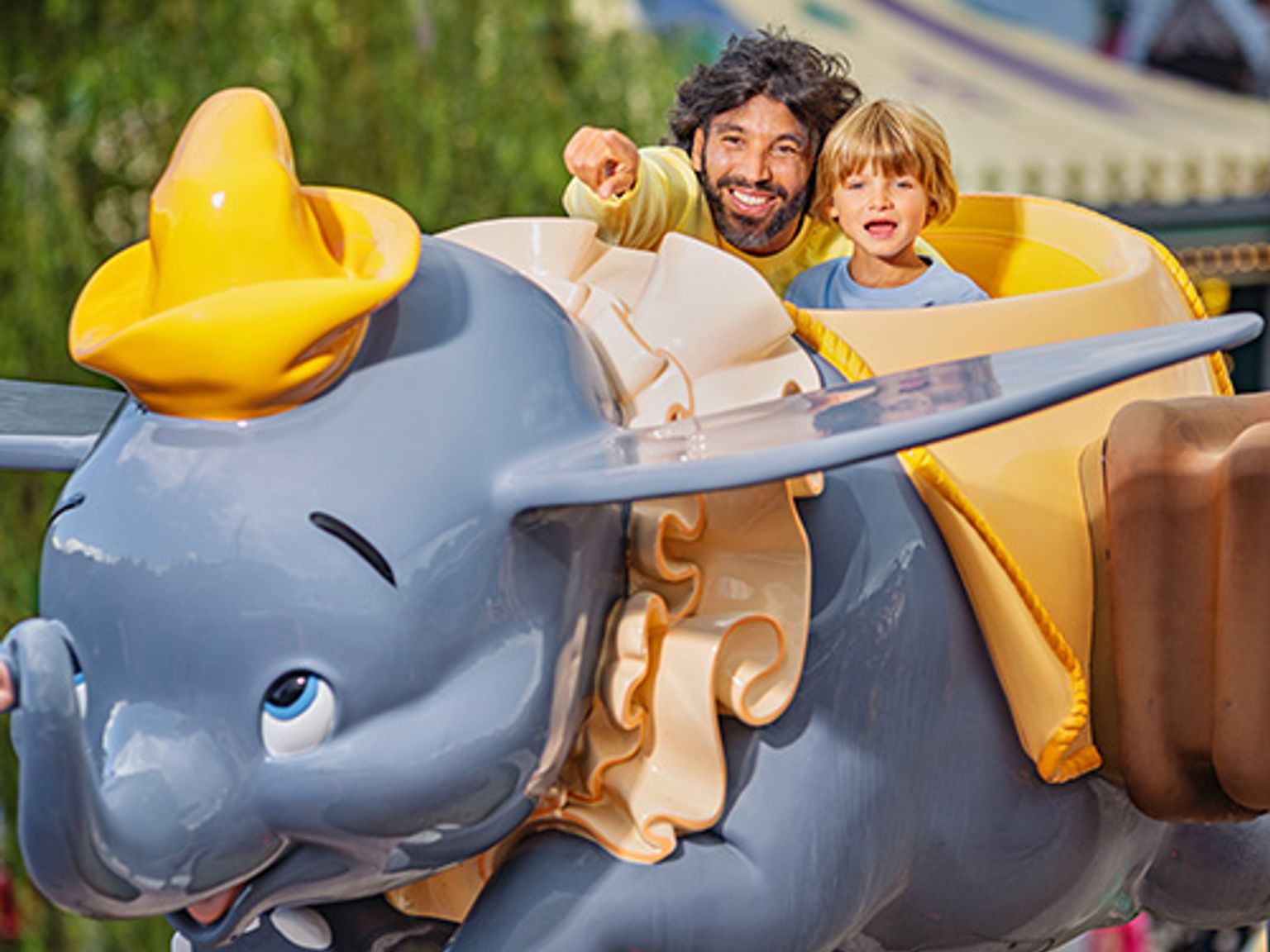 en man och ett barn rider dumbo elefantåkturen på disney world
