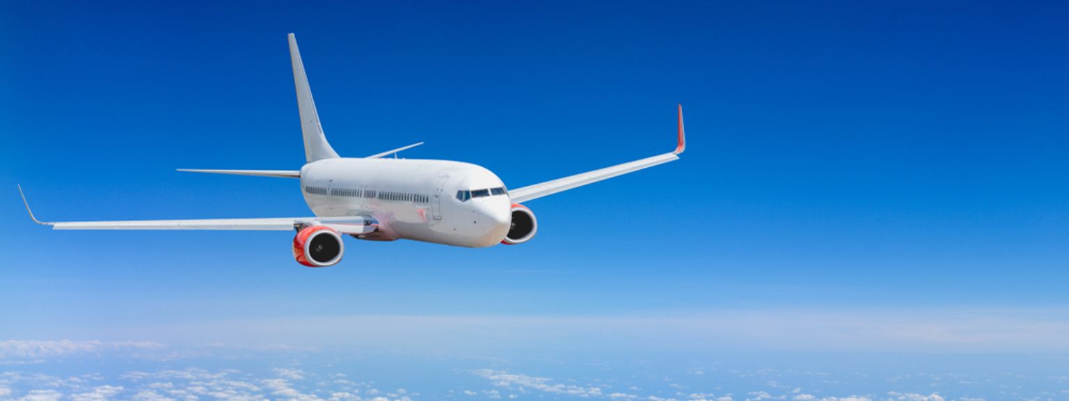 Et hvitt fly som flyr høyt over skyene på en blå himmel.