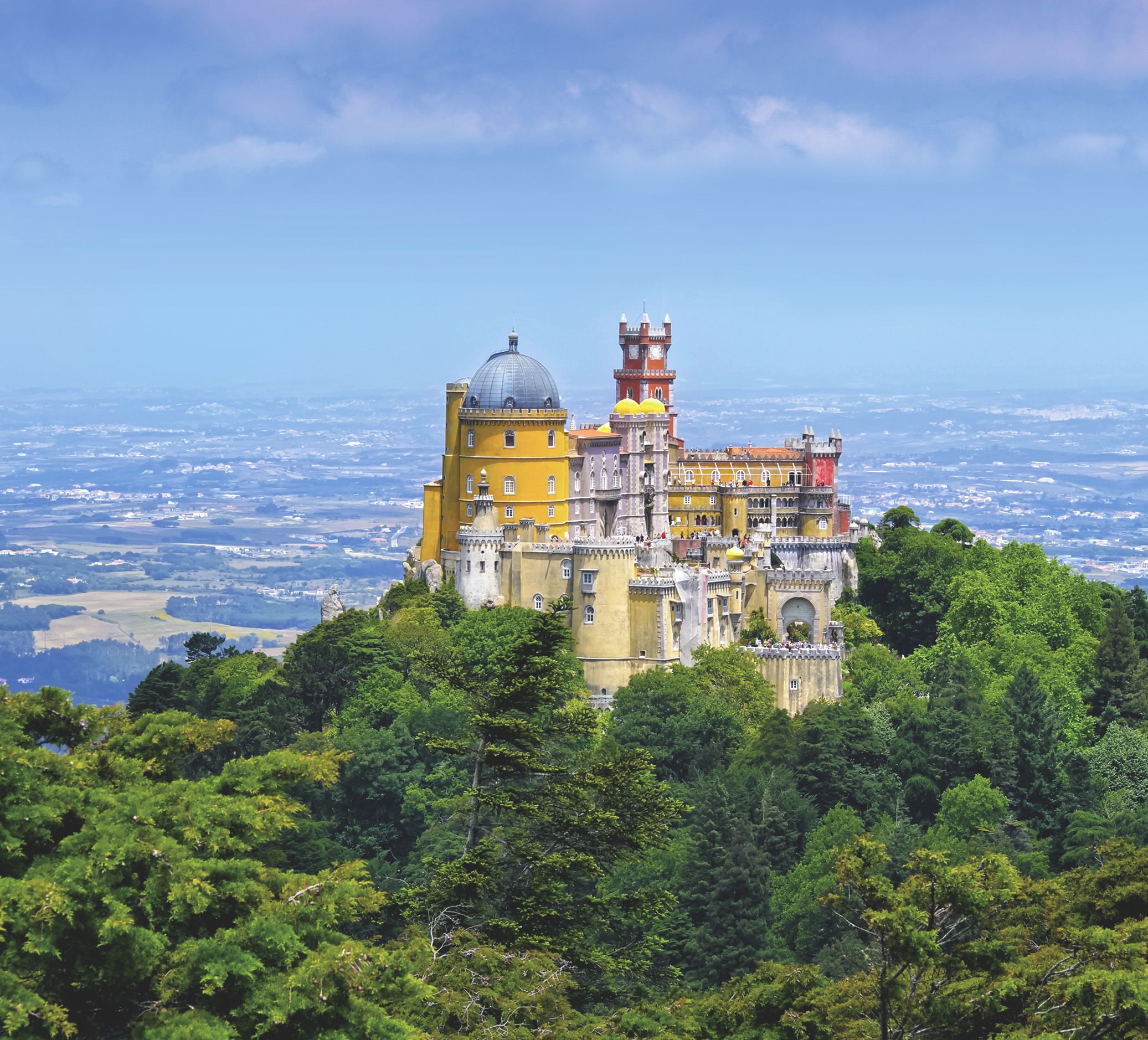 Färgglada Pena-palatset på en skogklädd kulle med utsikt över ett avlägset landskap.