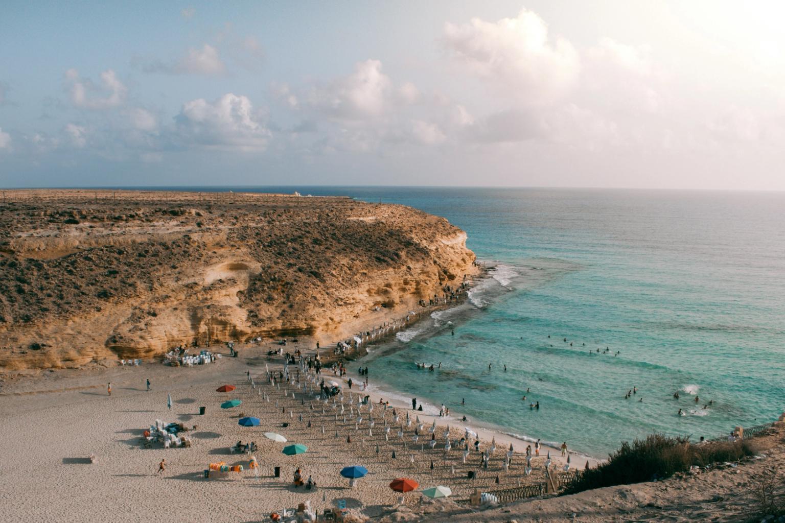 en flygvy över en strand fylld med människor och paraplyer