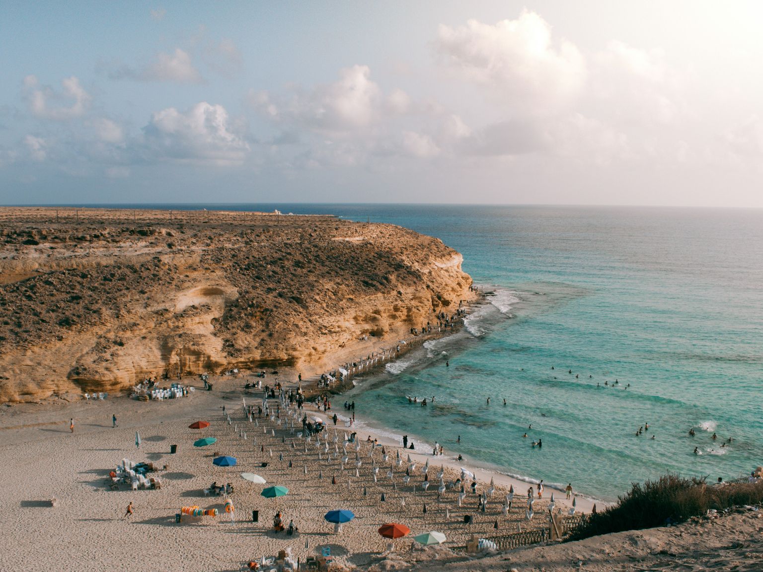 en flygvy över en strand fylld med människor och paraplyer