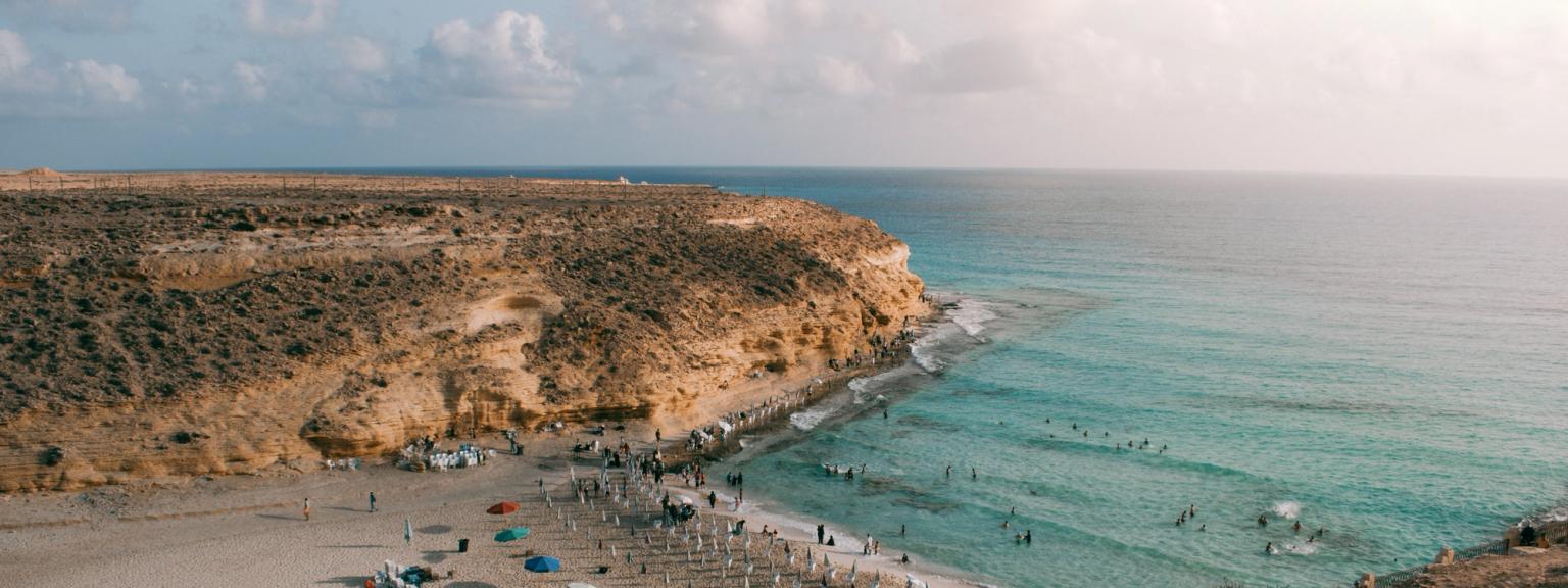 en flygvy över en strand fylld med människor och paraplyer