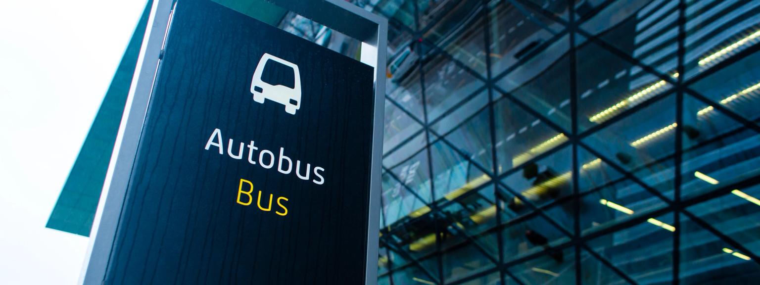 et busskilt er foran en glassbygning