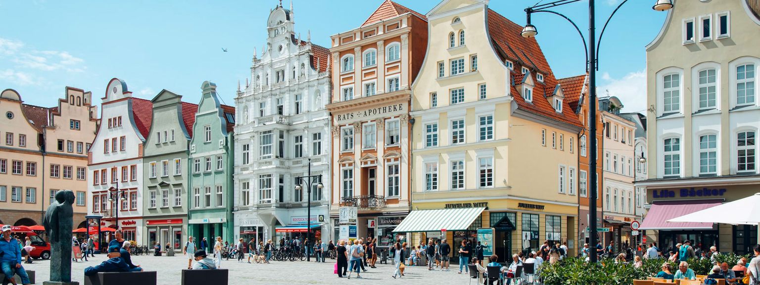 en stadstorg fylld med massor av byggnader och människor på en solig dag