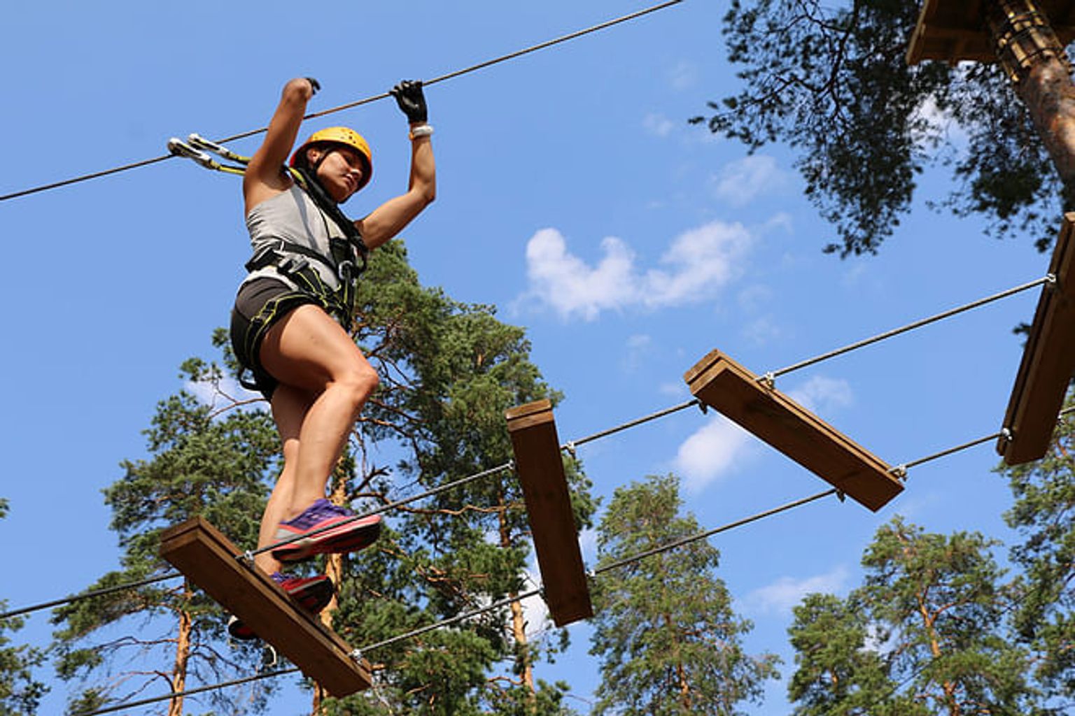 nainen seisoo köysikurssilla metsässä