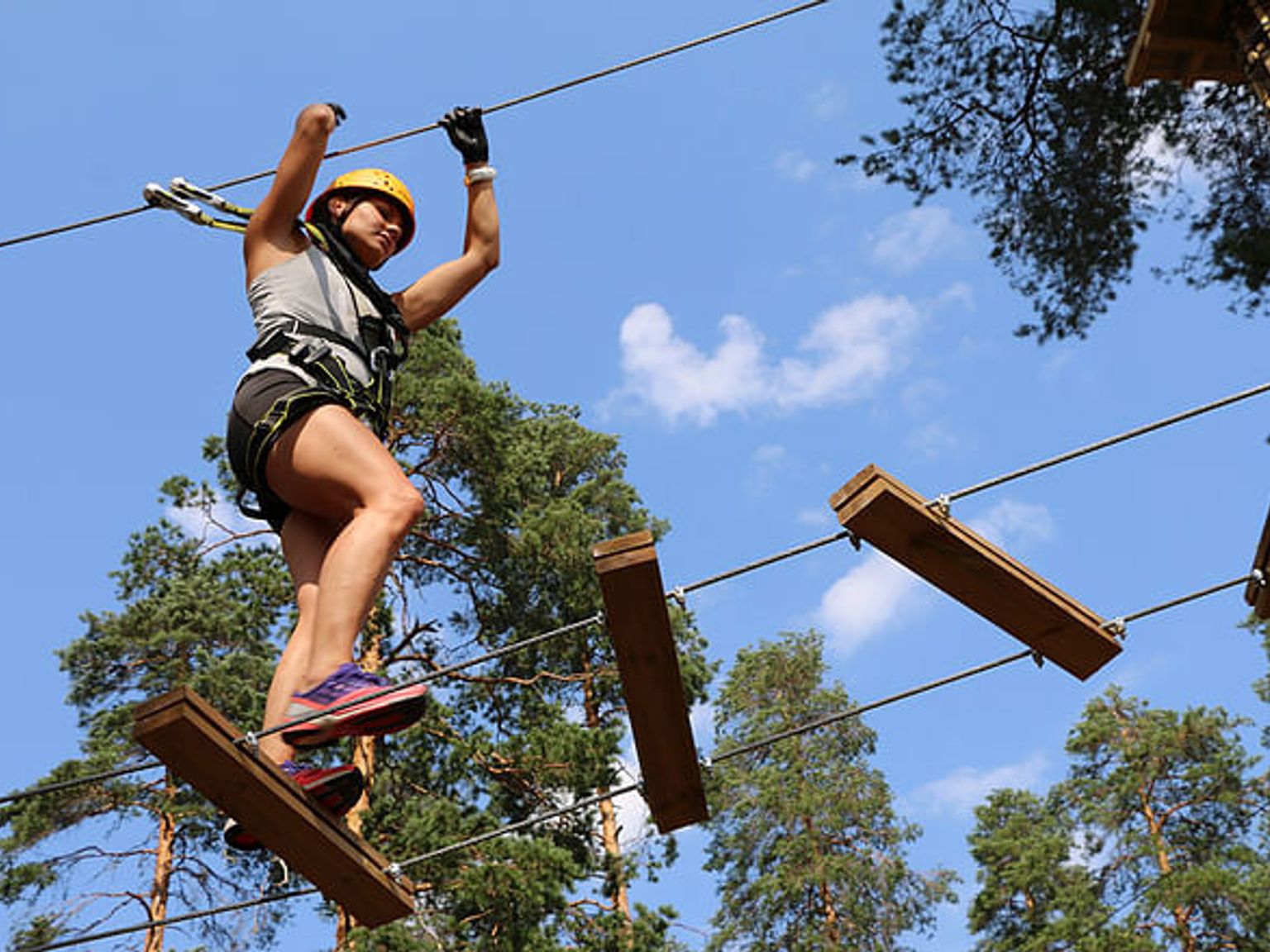 a woman is standing on a ropes course in the woods
