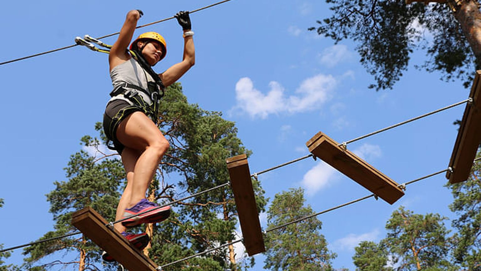 nainen seisoo köysikurssilla metsässä