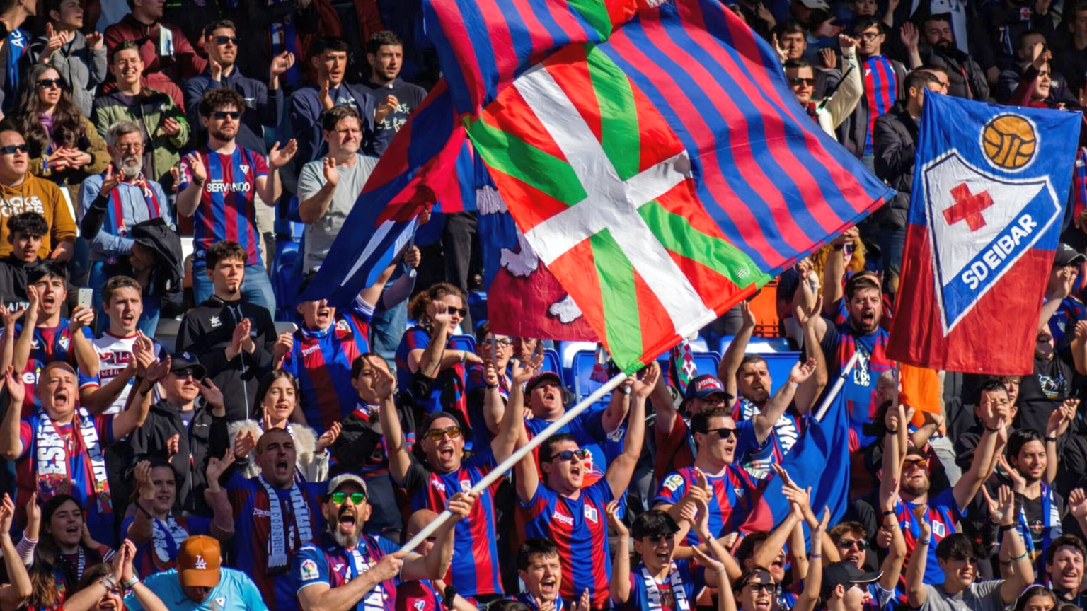 Fußballfans, die jubeln und baskische sowie SD-Eibar-Fahnen schwenken.