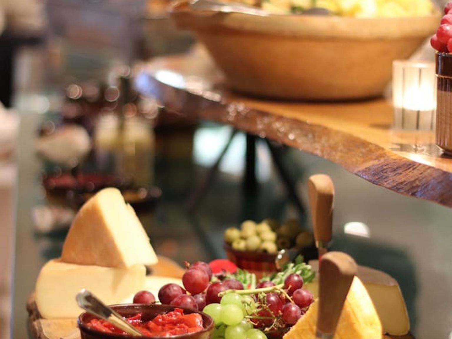 en tre skjærebrett med ost druer og saus på det