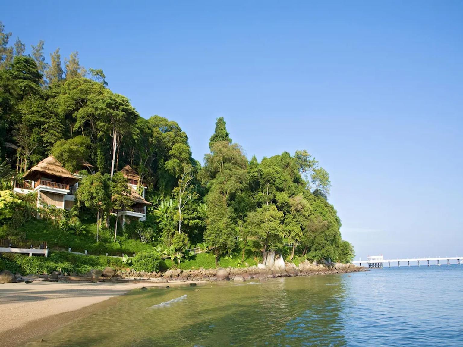 en strand med en mole og huse på en bakke med udsigt over havet