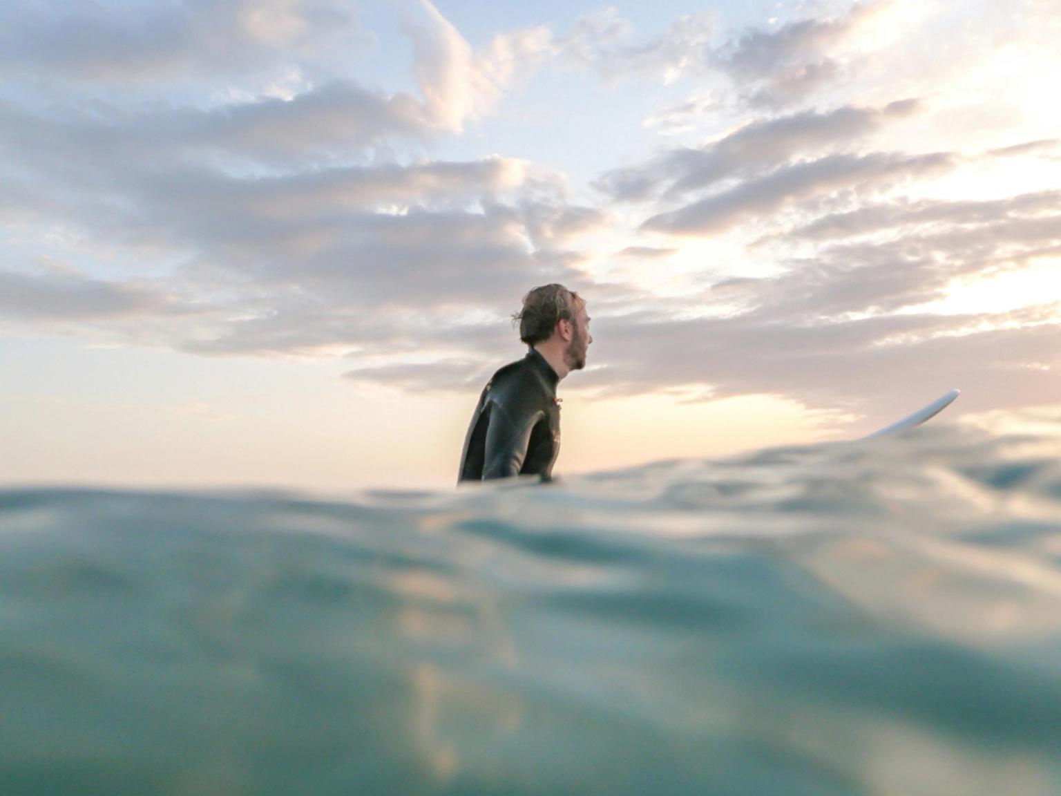 a man in a wetsuit is holding a surfboard in the ocean