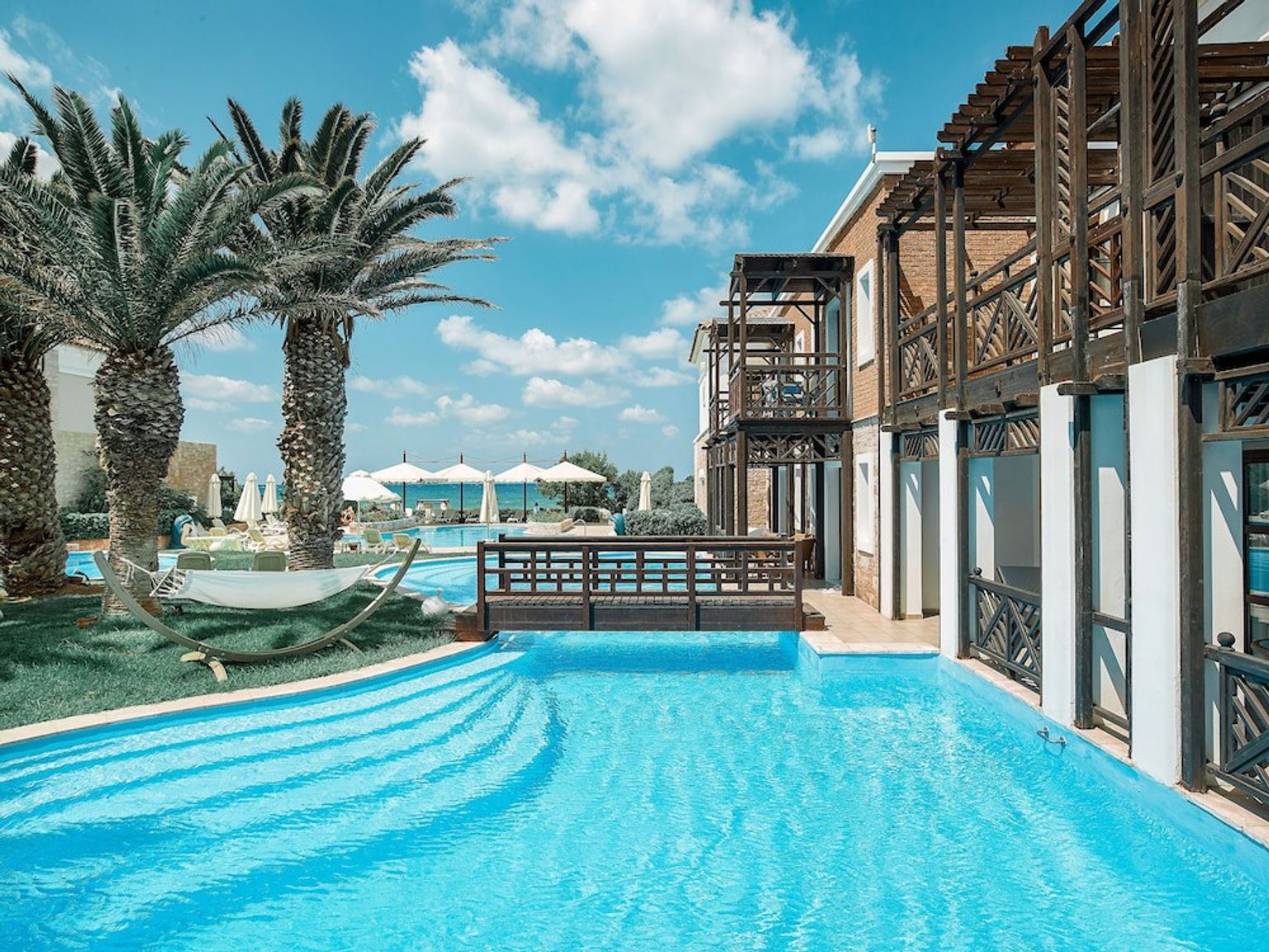 ein großer Swimmingpool umgeben von Palmen und einer Brücke