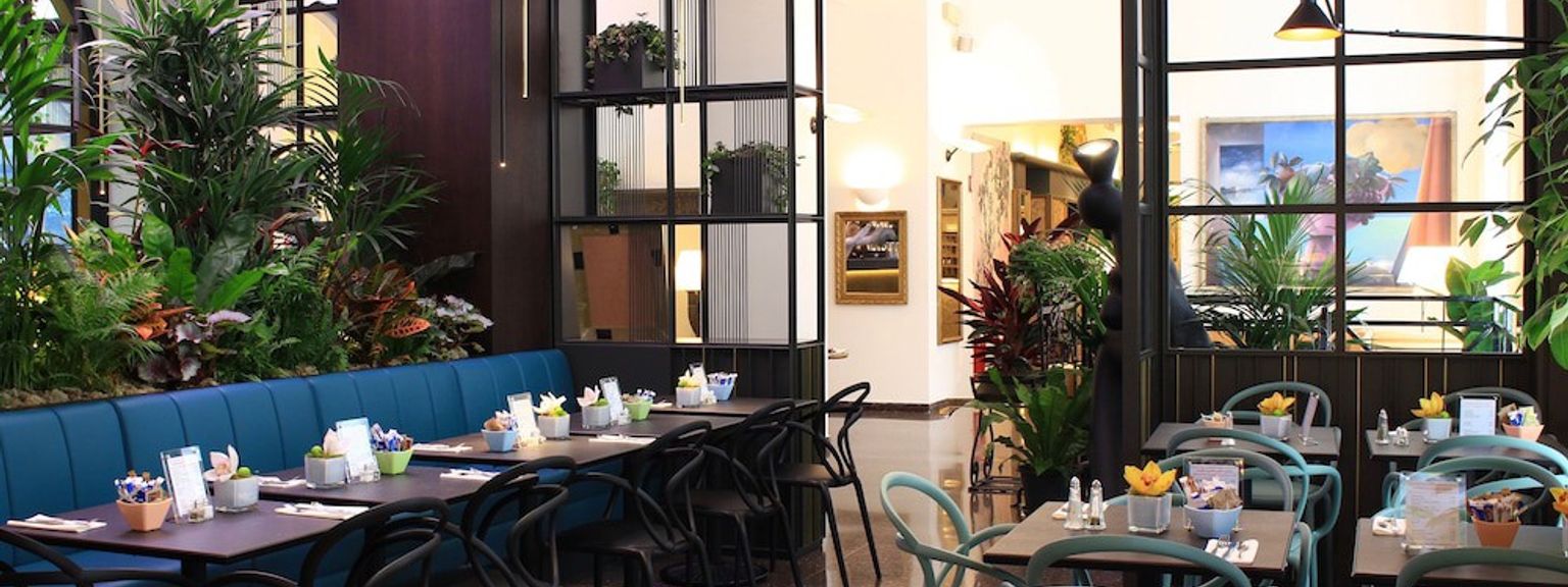 ein Restaurant voller Tische und Stühle und Pflanzen