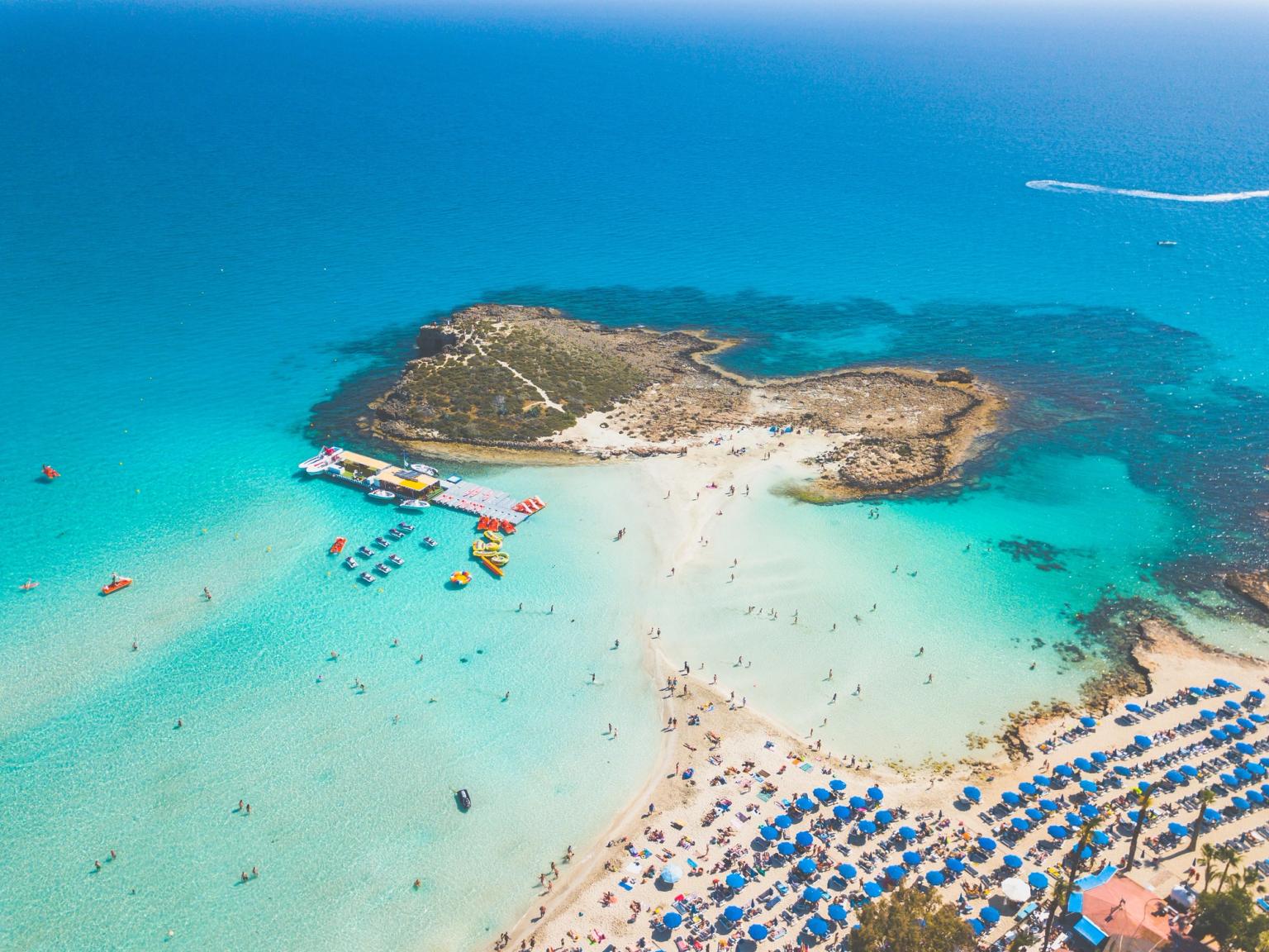 en luftig utsikt over en tropisk strand fylt med mennesker og paraplyer