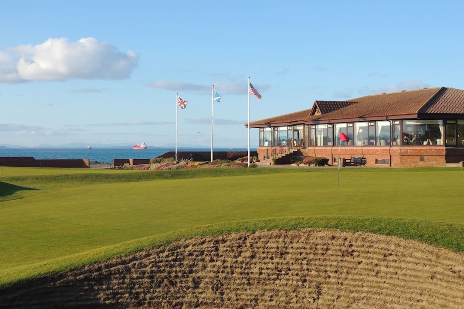 en golfbane med en klubbhus i bakgrunnen og en grønn i forgrunnen
