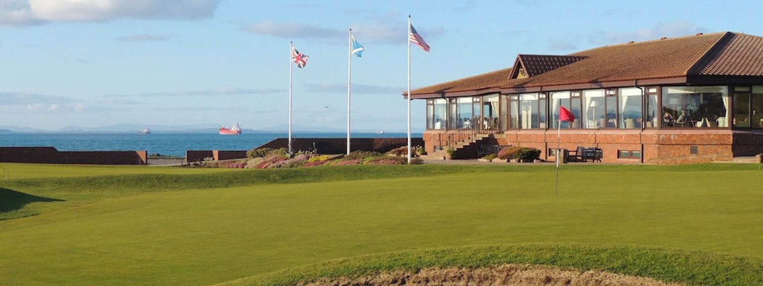 en golfbana med en klubbstuga i bakgrunden och en grön i förgrunden