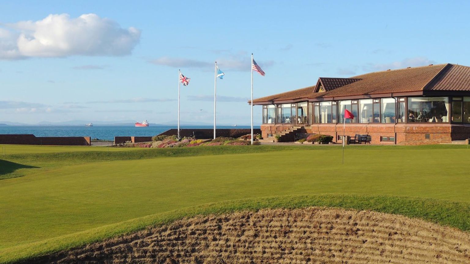 en golfbane med en klubbhus i bakgrunnen og en grønn i forgrunnen