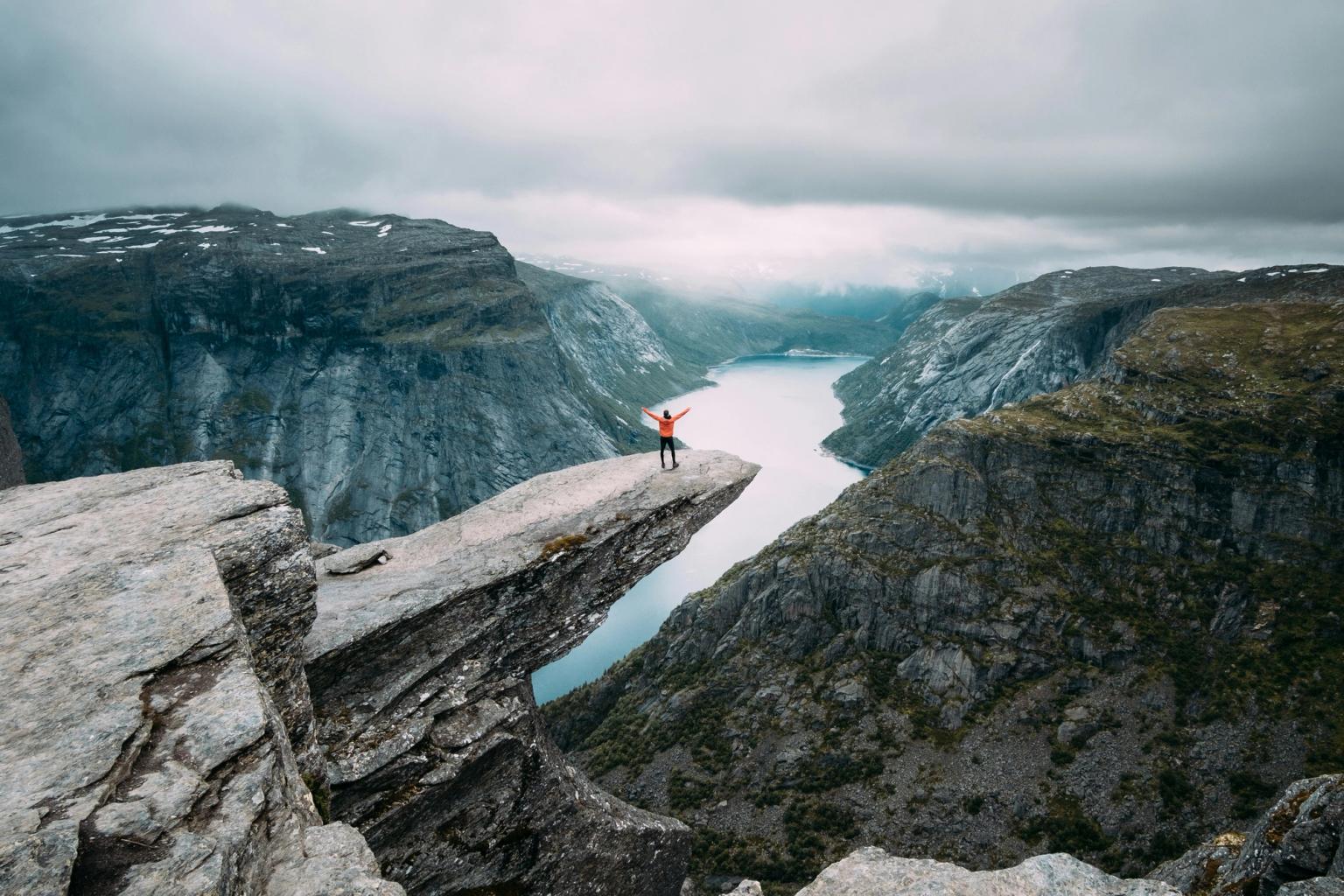 a person is standing on the edge of a cliff overlooking a river