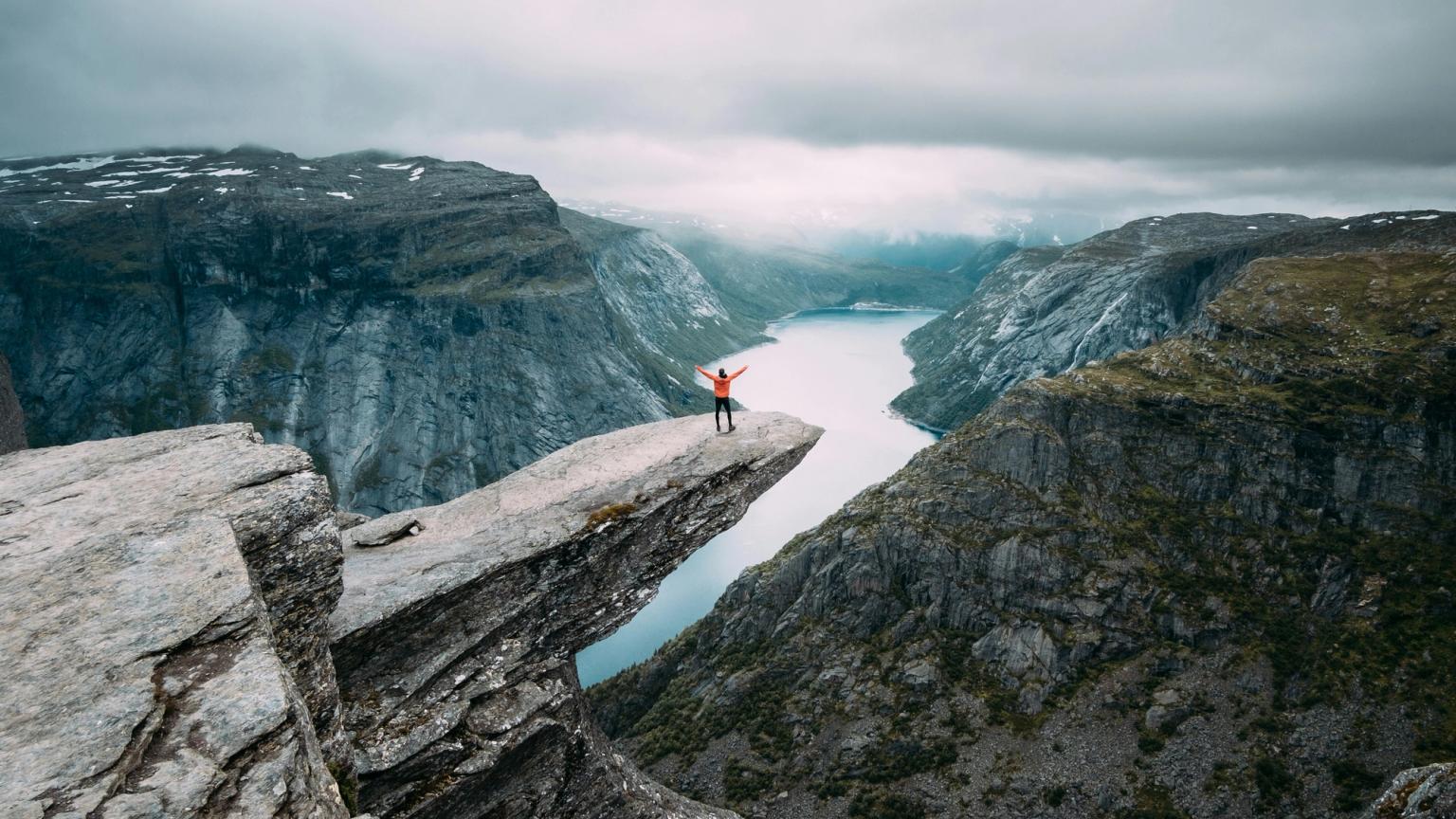 a person is standing on the edge of a cliff overlooking a river