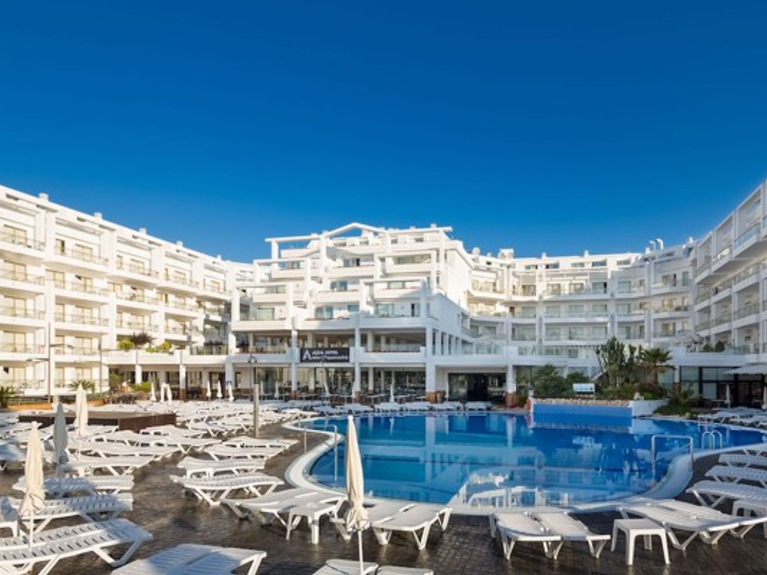 ett stort vitt hotell med en stor simbassÀng framför det