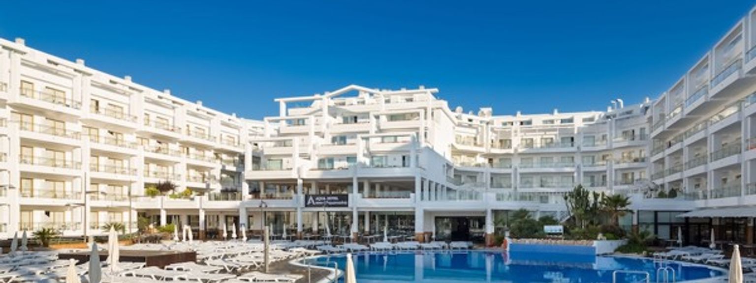 ett stort vitt hotell med en stor simbassÀng framför det