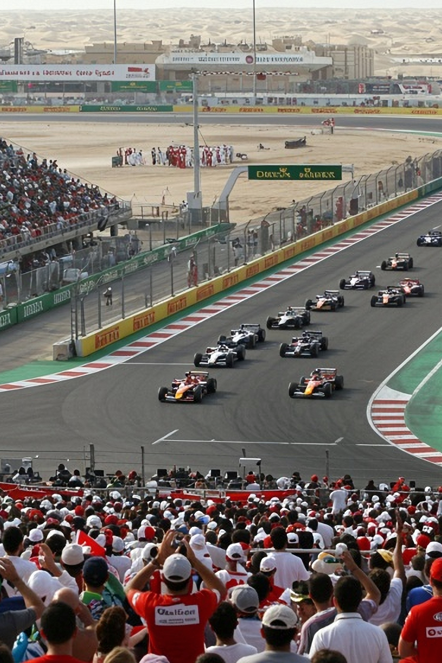 Avo-ohjaamolliset kilpa-autot aavikkoradalla, katsomot täynnä katsojia.