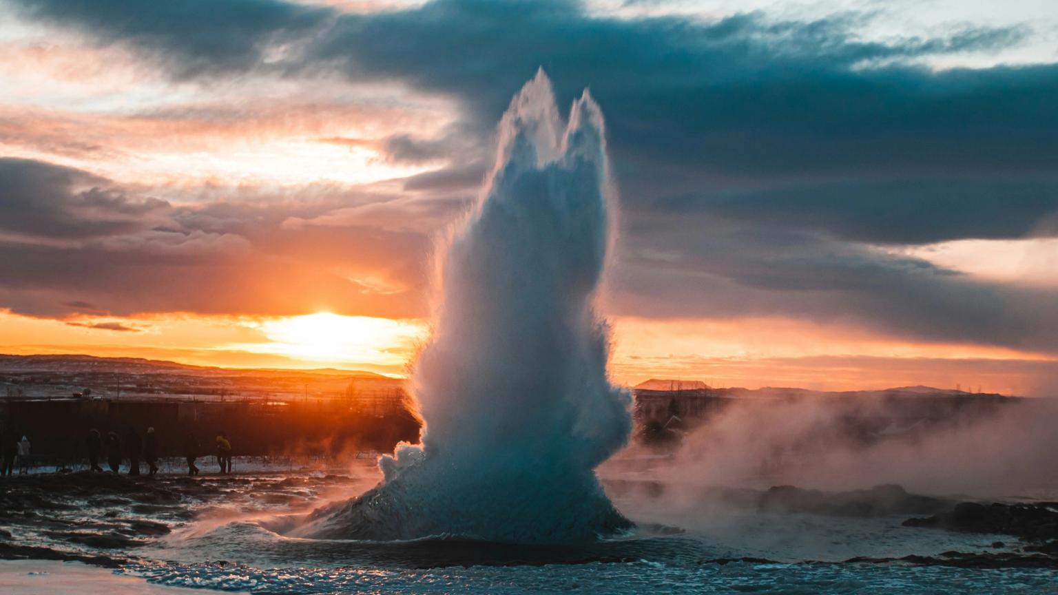 un géiser está erupcionando en el océano al atardecer
