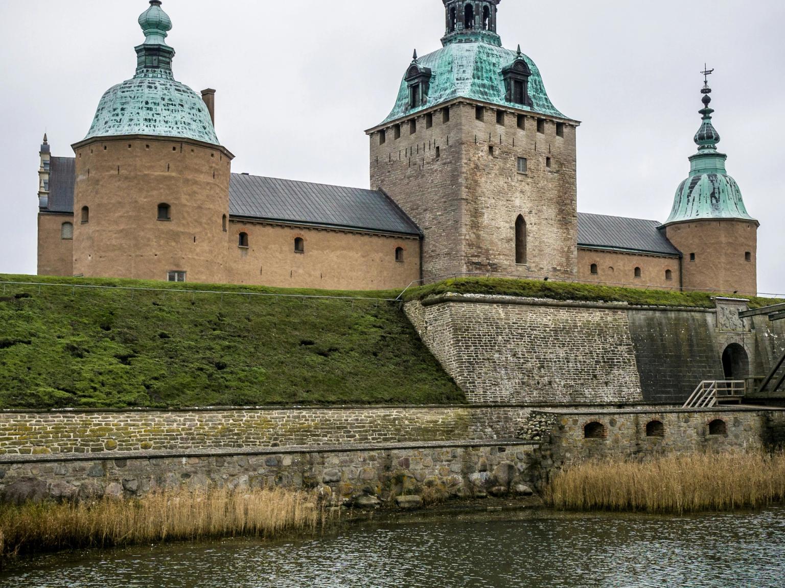 a large castle is sitting on top of a hill next to a body of water