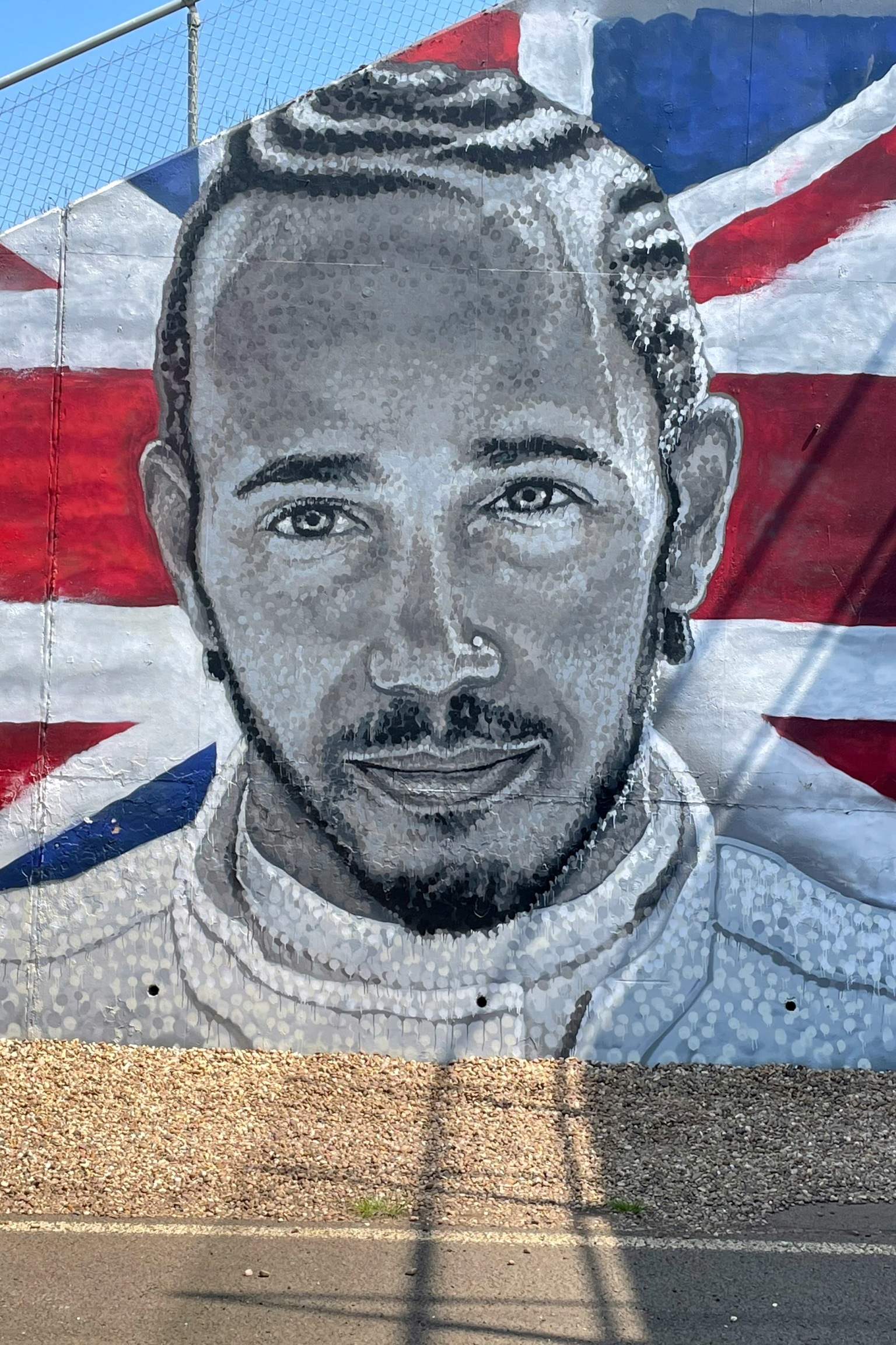 Mural of Lewis Hamilton in grayscale against a British Union Jack flag.