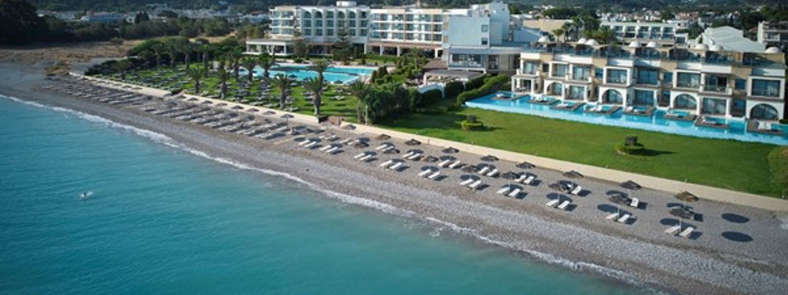 en flygvy över en strand med paraplyer och ett hotell i bakgrunden