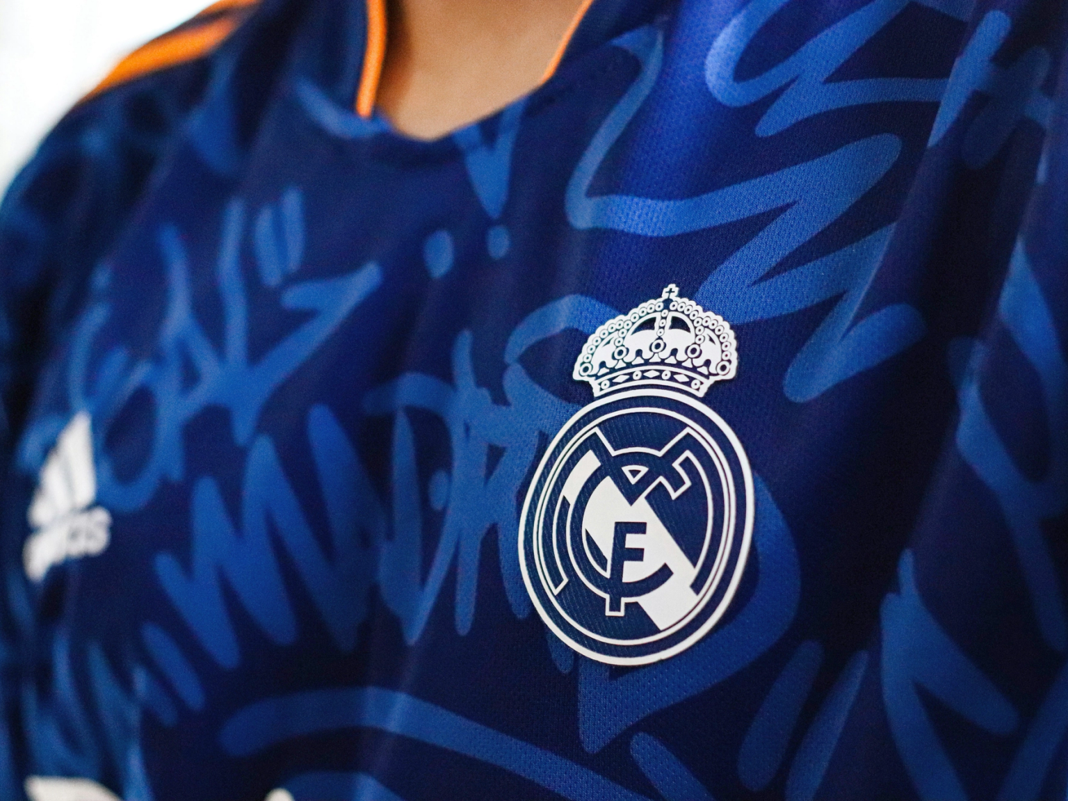 Blue Real Madrid soccer jersey with white logos and a graffiti pattern.