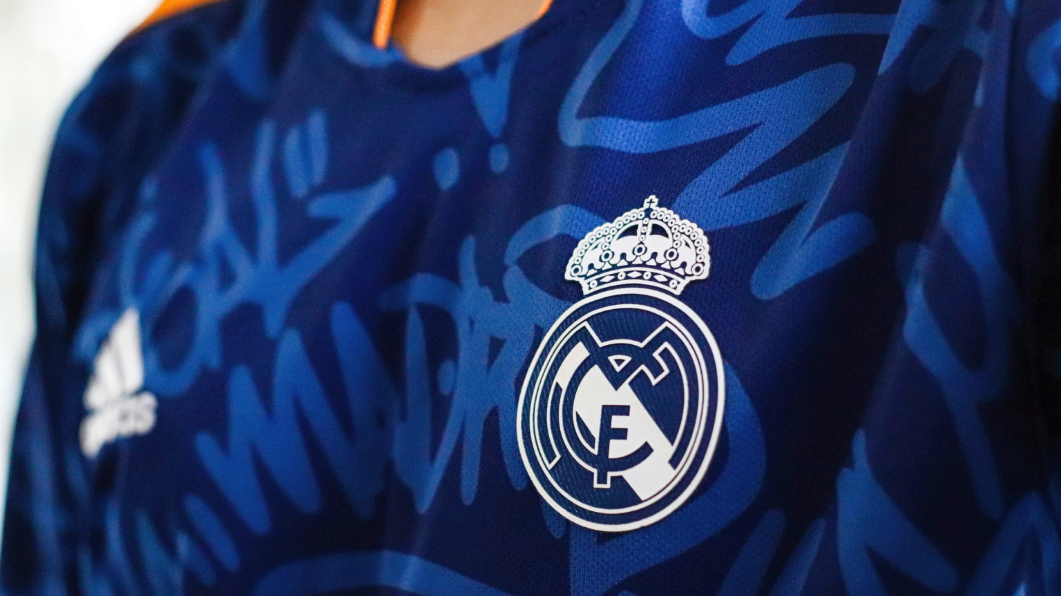 Blue Real Madrid soccer jersey with white logos and a graffiti pattern.