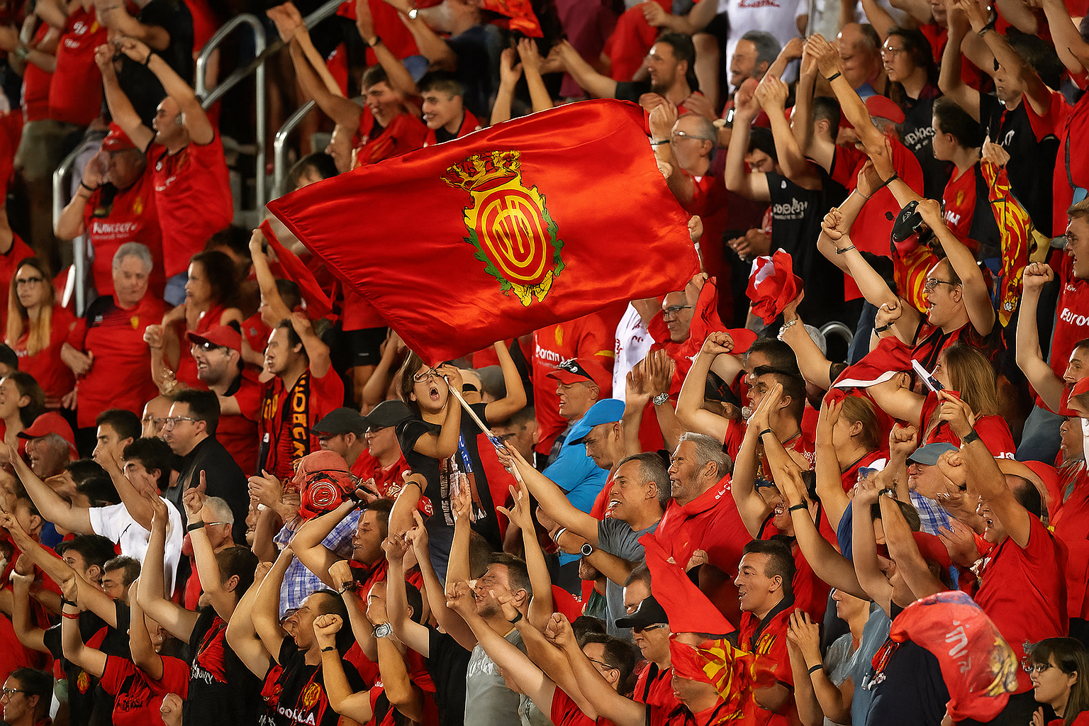 Exalterade fans i rött jublar, med en Real Mallorca-flagga som vajar.