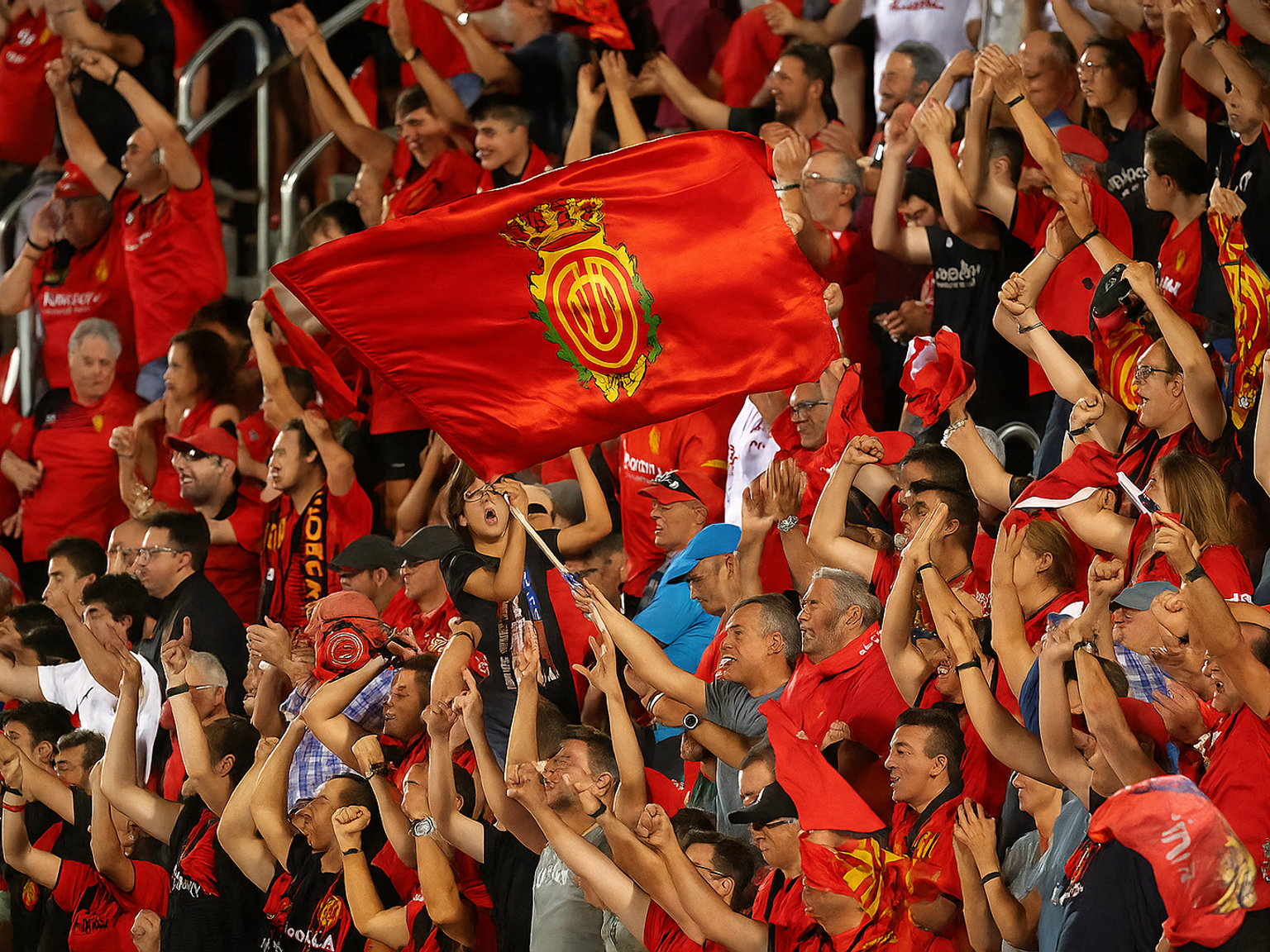 Exalterade fans i rött jublar, med en Real Mallorca-flagga som vajar.