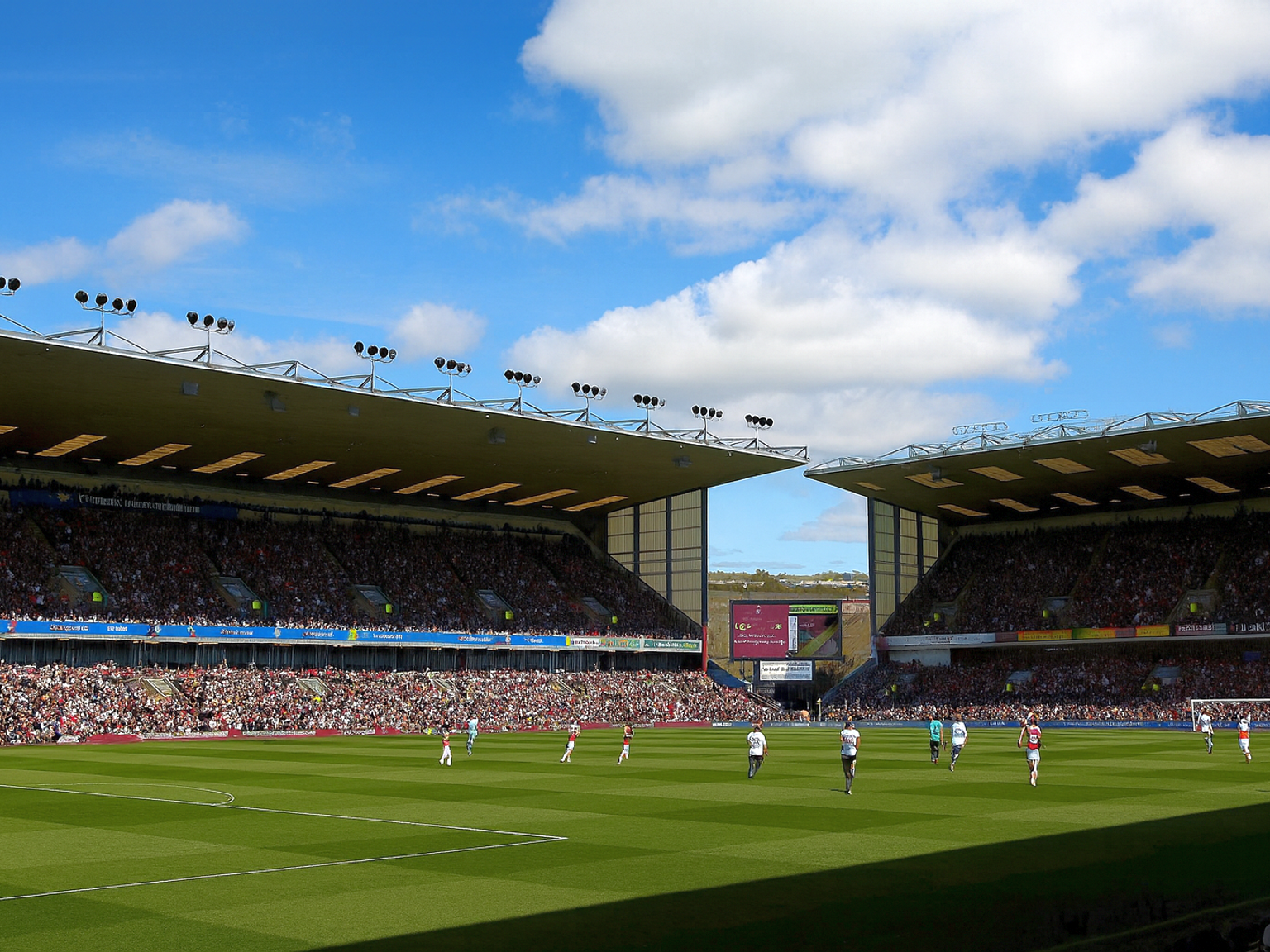 Une vue large d'un stade de football rempli de fans sous un ciel ensoleillé, avec des joueurs sur le terrain vert.