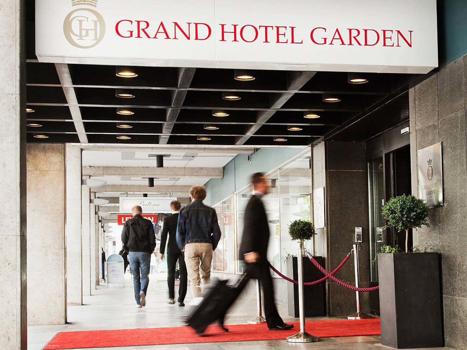 en grupp människor går nerför en röd matta framför Grand Hotel Garden.