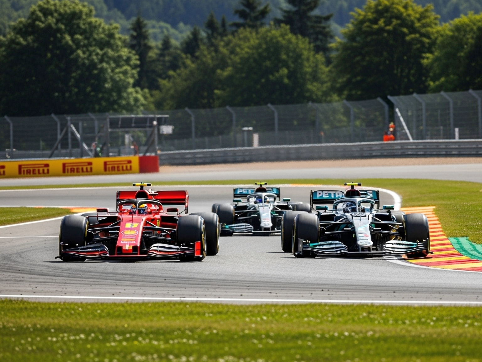 A red Formula 1 car leads two dark grey and teal F1 cars on a race track with green hills in the background.