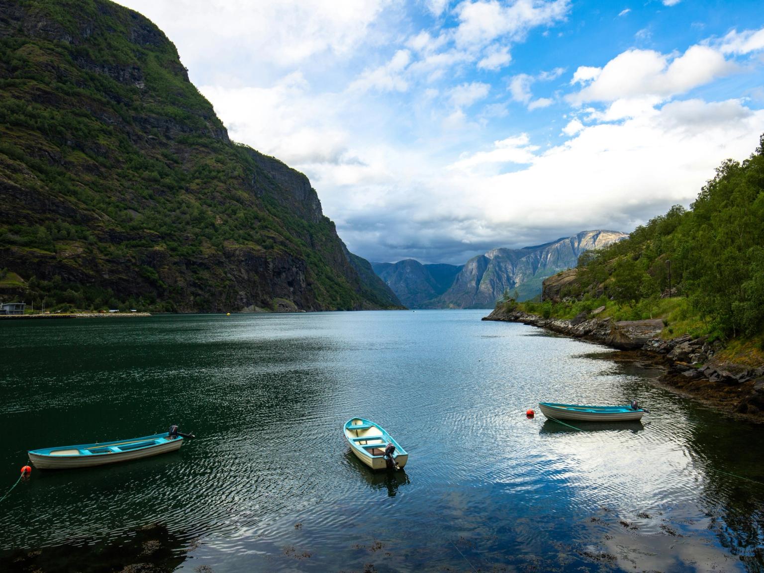 dos barcos están flotando en un lago rodeado de montañas