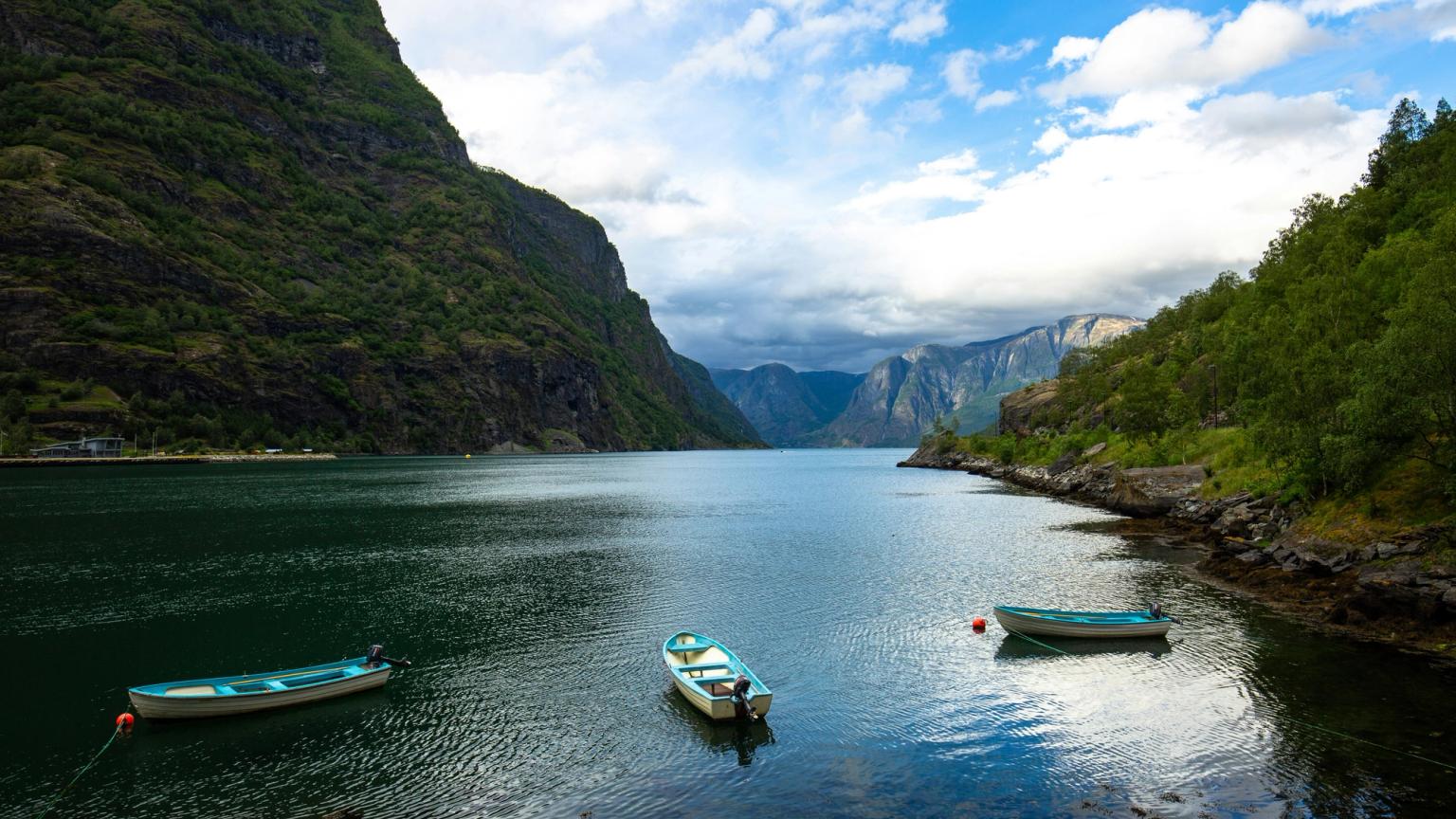 two boats are floating on a lake surrounded by mountains