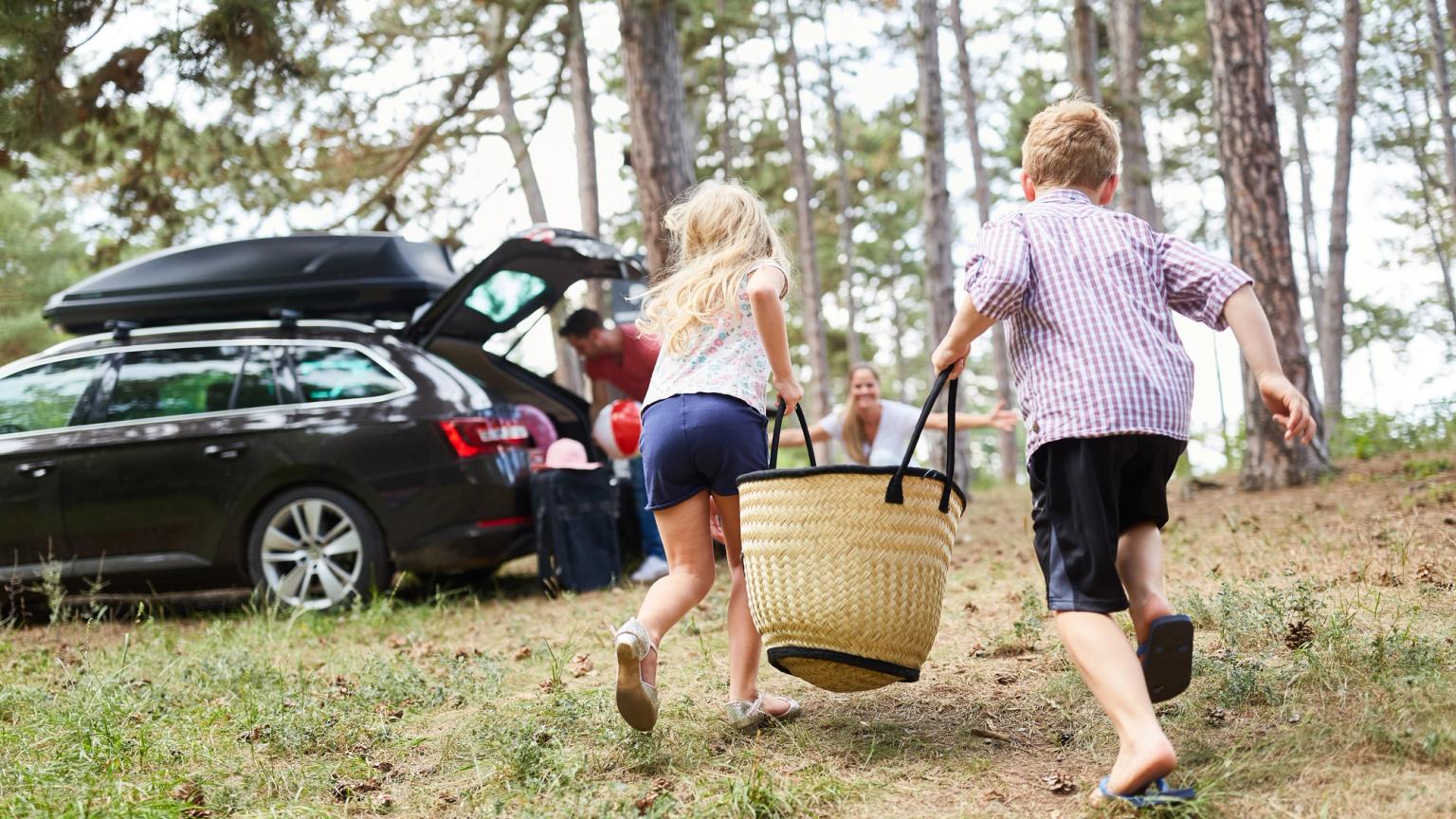 eine Gruppe von Kindern läuft auf ein Auto mit einem Picknickkorb zu