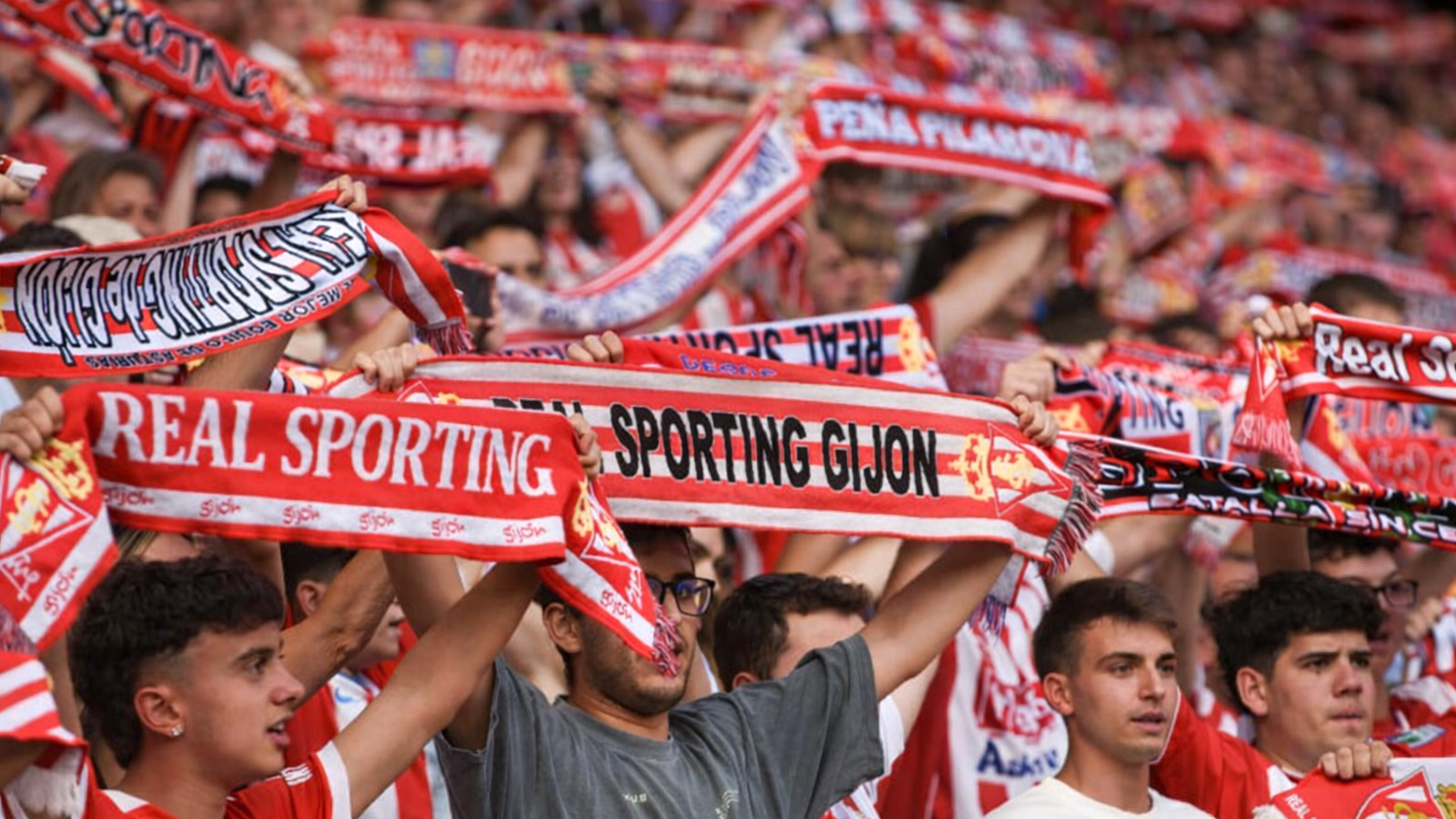 En folkmassa av fotbollsfans håller upp rödvita Real Sporting Gijón-halsdukar.