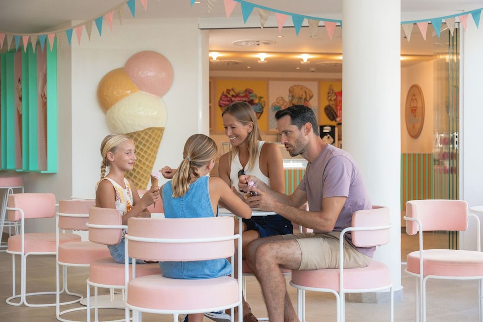 Una familia de cuatro disfruta de un helado en una heladería colorida y moderna con decoraciones divertidas. Iberostar Selection Albufera Playa - Todo Incluido