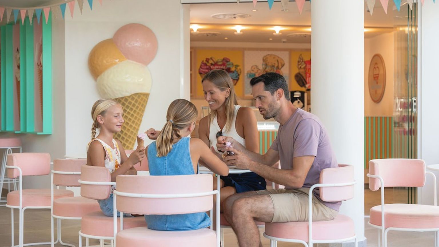 Una familia de cuatro disfruta de un helado en una heladería colorida y moderna con decoraciones divertidas. Iberostar Selection Albufera Playa - Todo Incluido