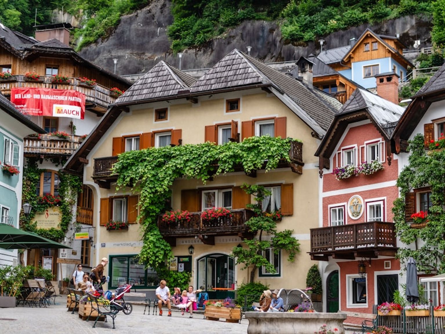 en grupp människor sitter utanför en byggnad i en liten stad.