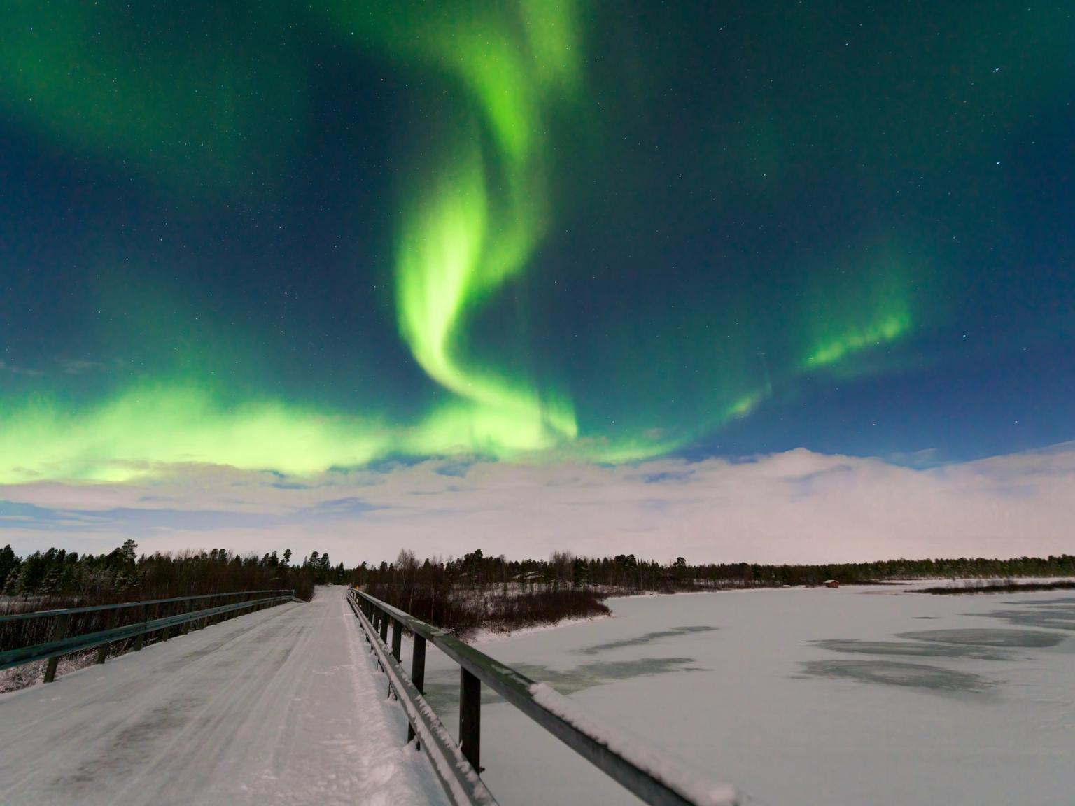 aurora borealis är synlig över en bro över en frusen sjö