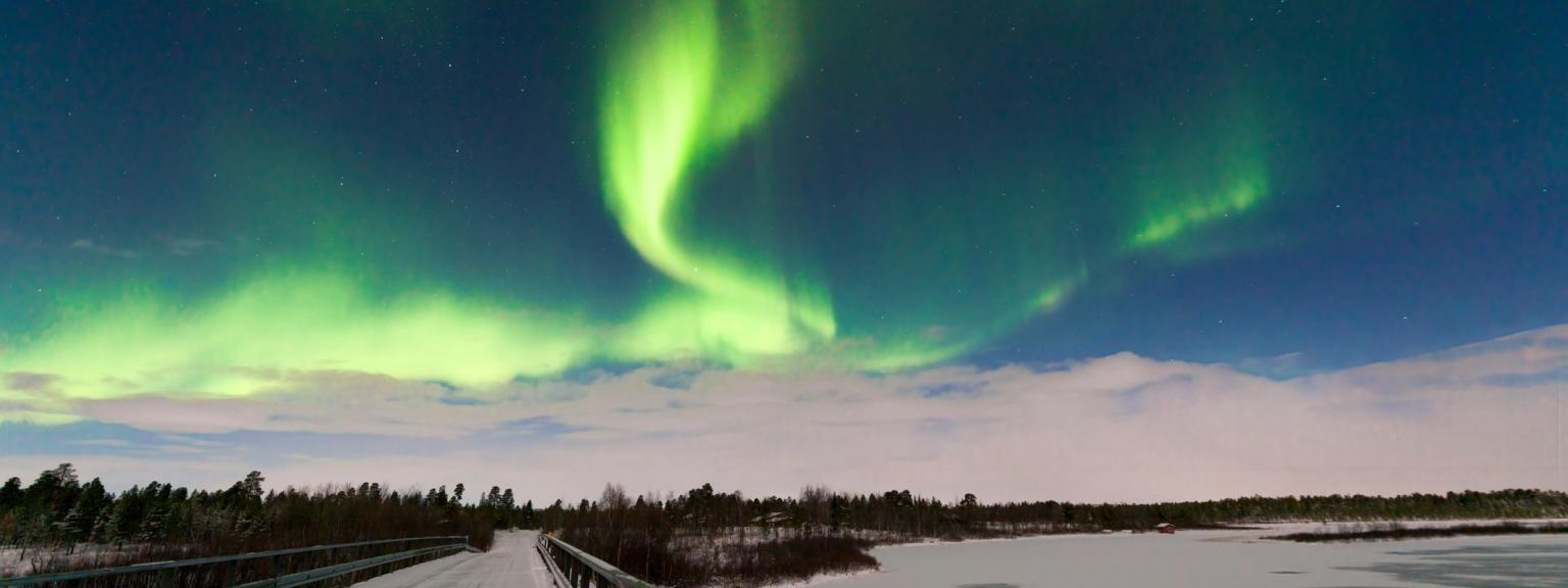 aurora borealis är synlig över en bro över en frusen sjö