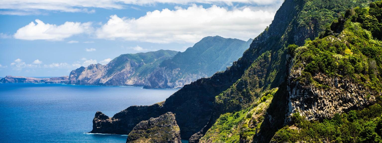 en vy av en klippa på Madeira med utsikt över havet med berg i bakgrunden.