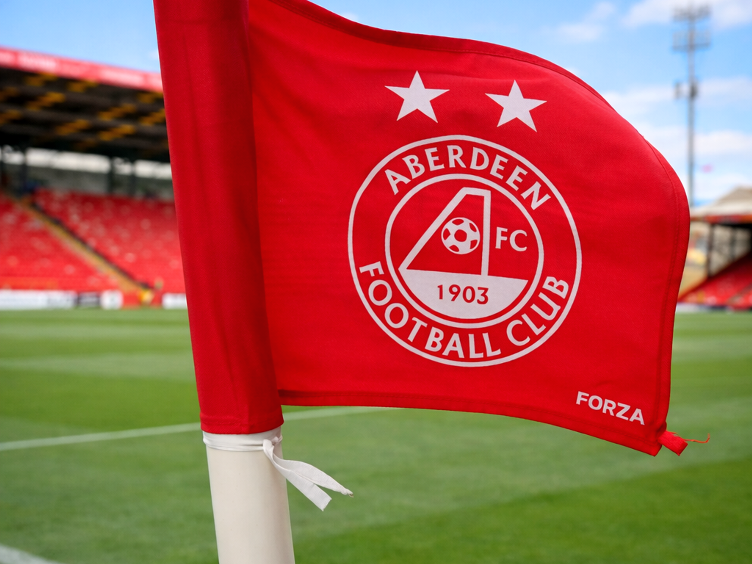 Et rødt Aberdeen FC hjørneflag står på en fodboldbane på et stadion.