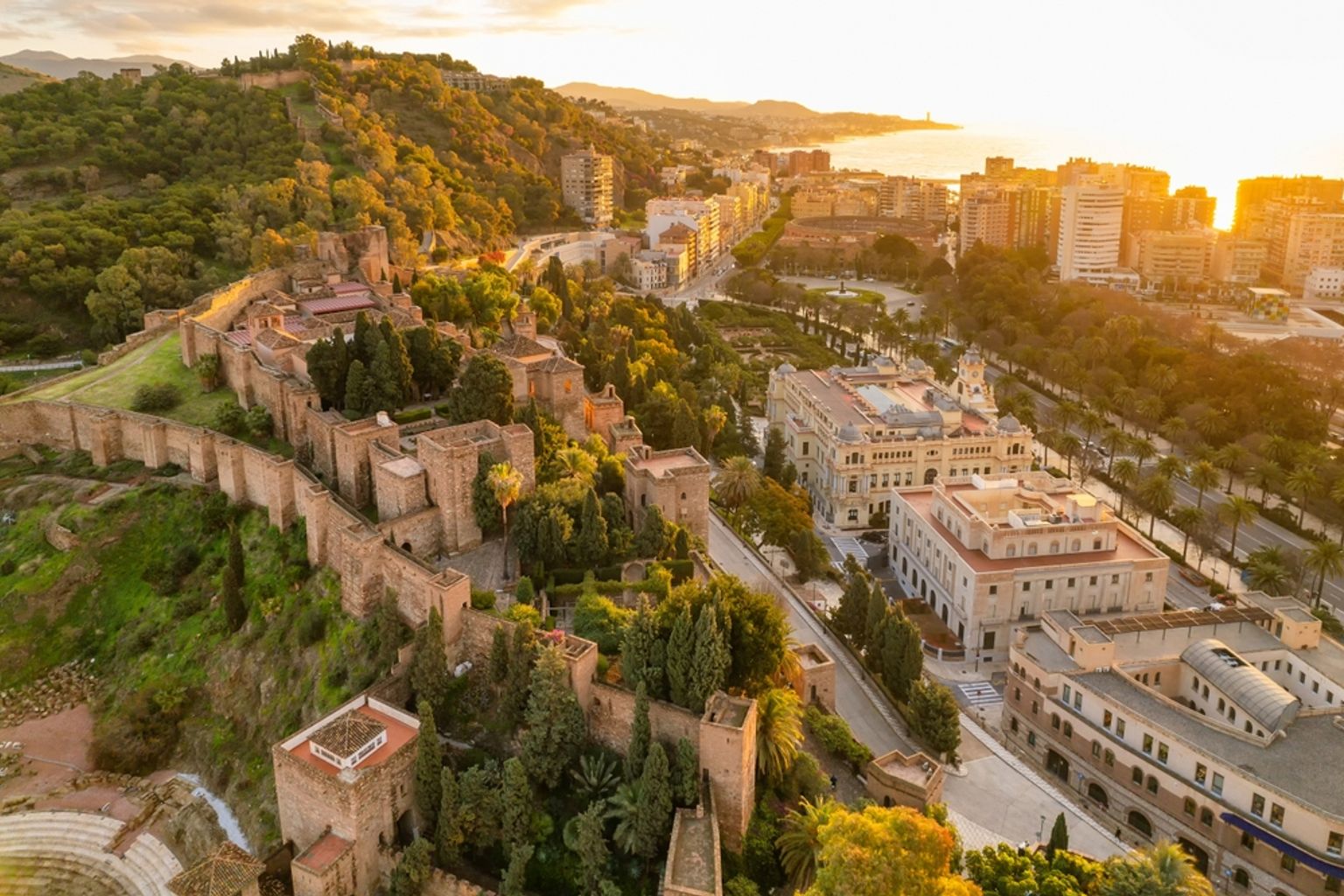 Flygfoto över Alcazaba-fästningen i Málaga med utsikt över staden och bukten vid solnedgången.